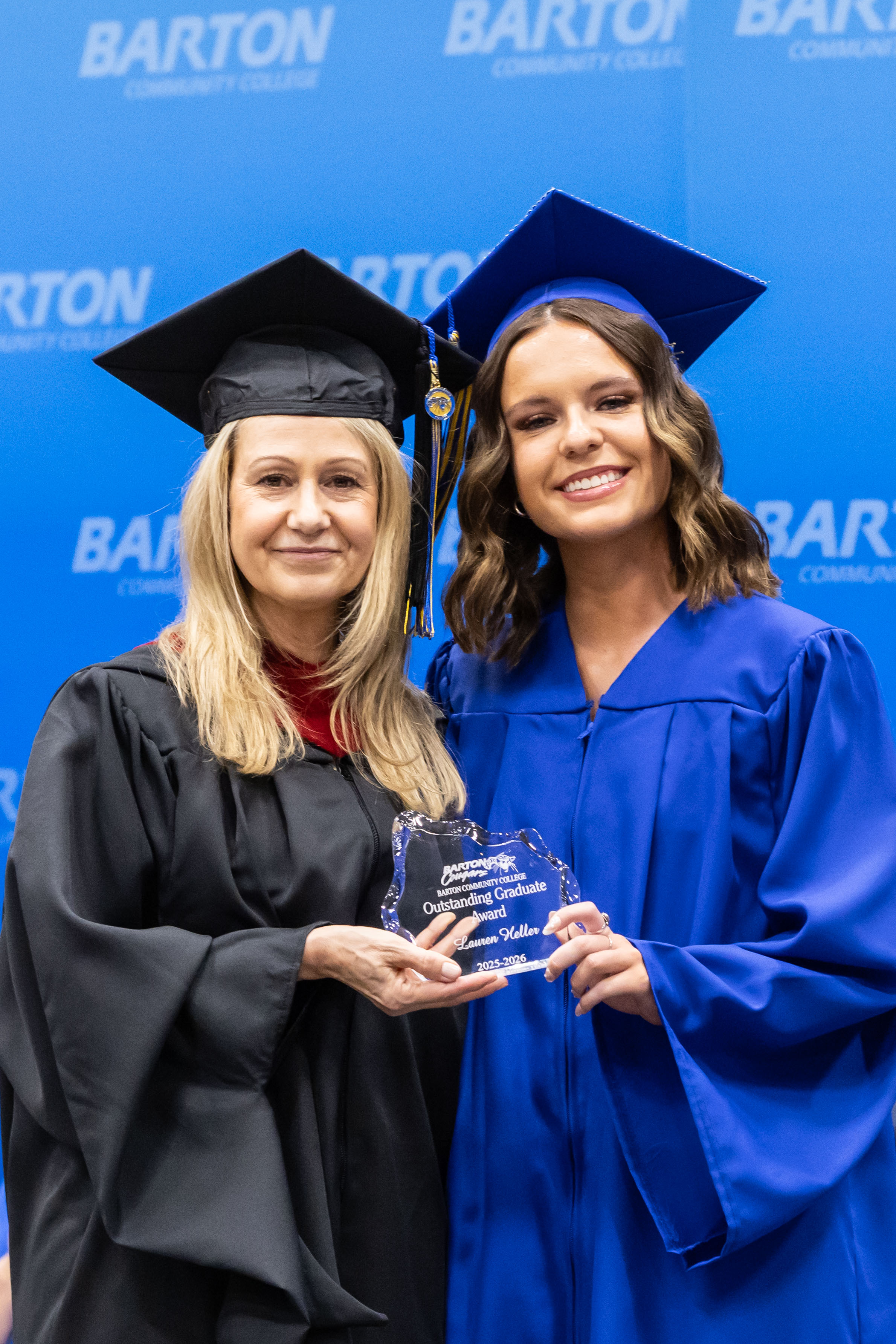 administrator holding an award with a female student