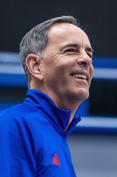 photo of man smiling in blue athletic looking jacket that is blue