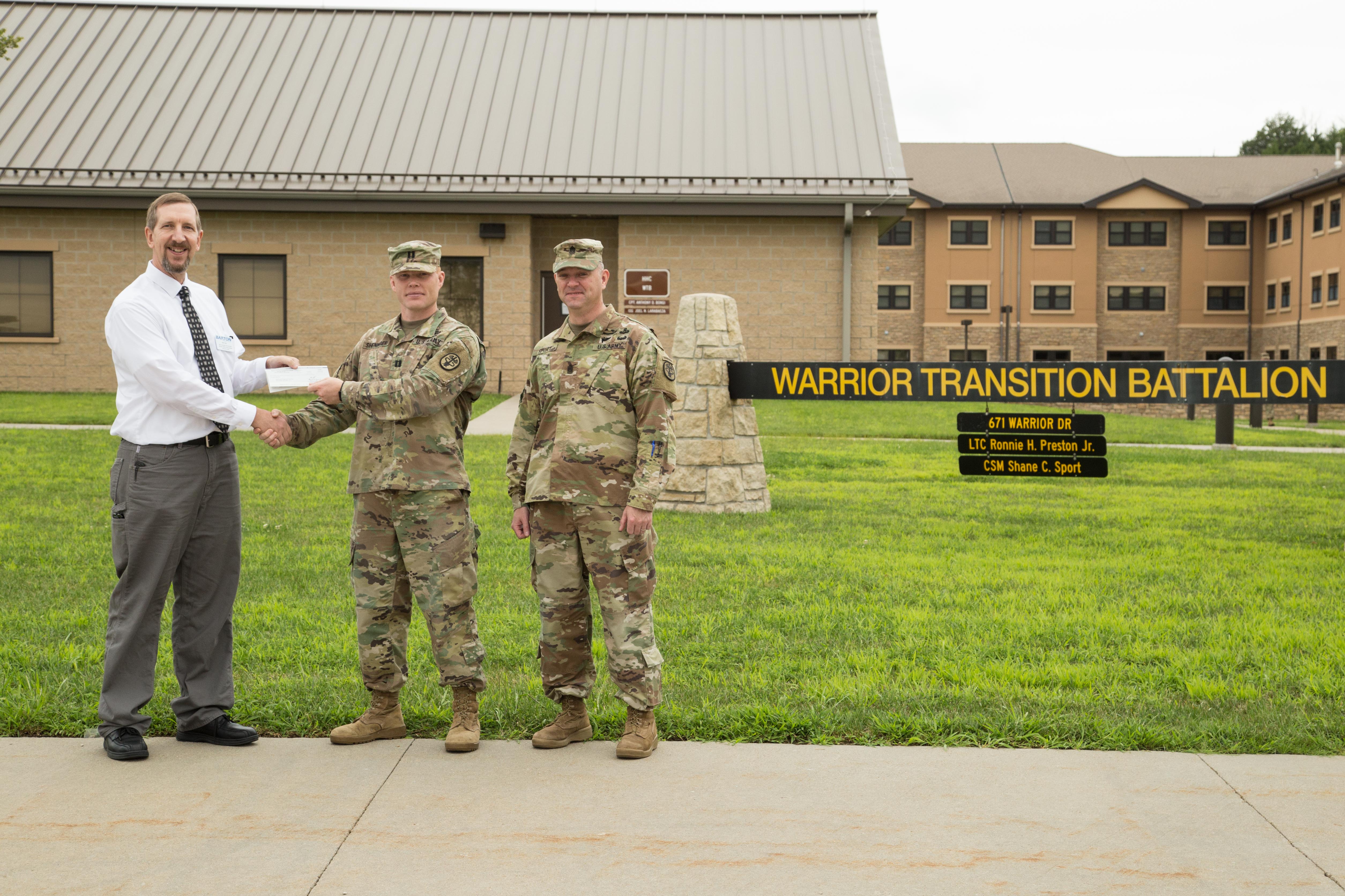 Kurt Teal, Dean of Fort Riley Academics, Technical Education and Military Outreach Programs at Barton Community College, presents a check for $3,250 to Bravo Company Commander Daniel Sheninger and Command Sergeant Major Shane Sport.