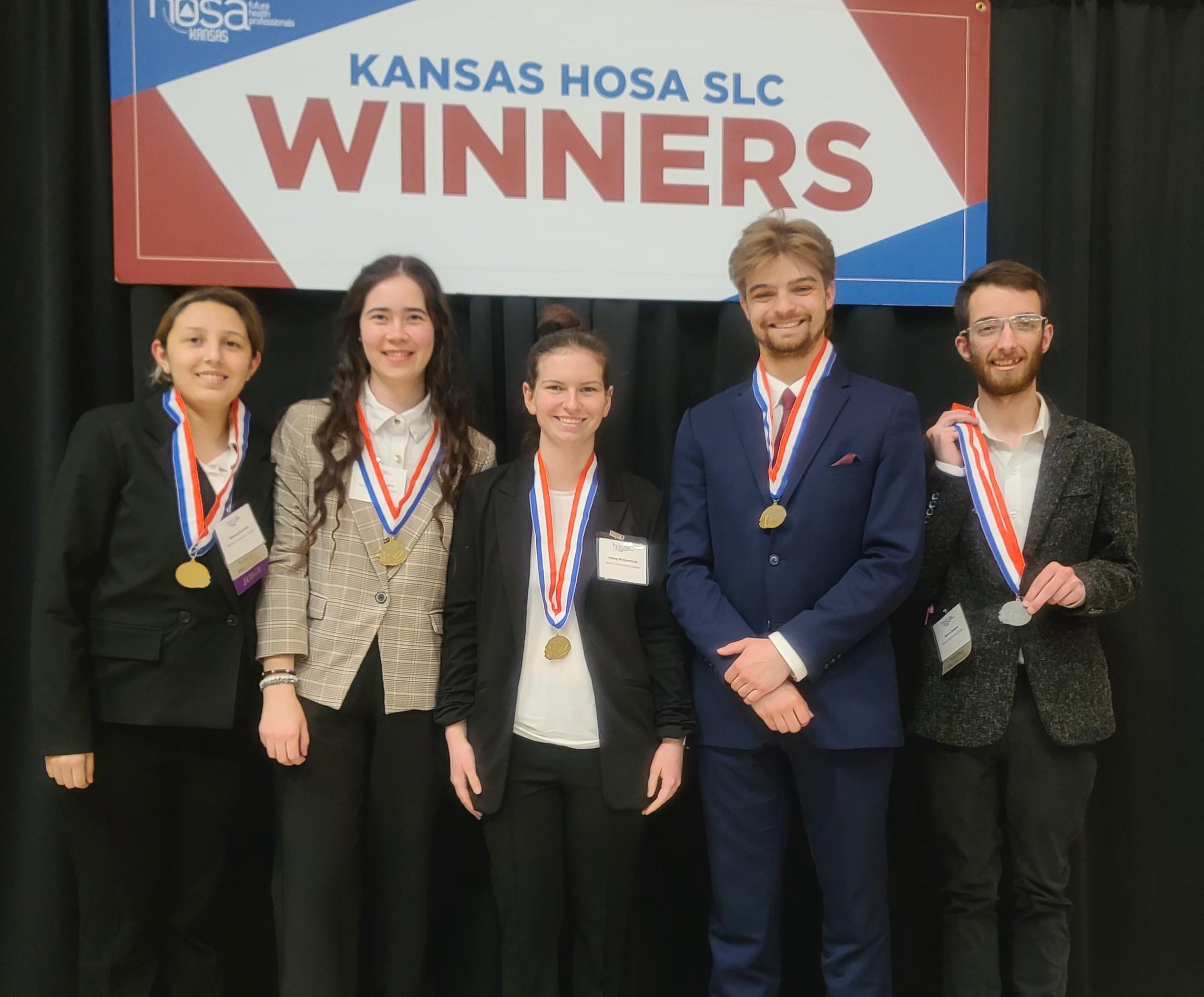 students in formal wear with medals around necks