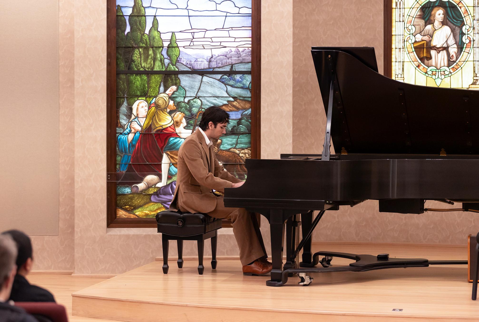 male student playing  piano in a suit