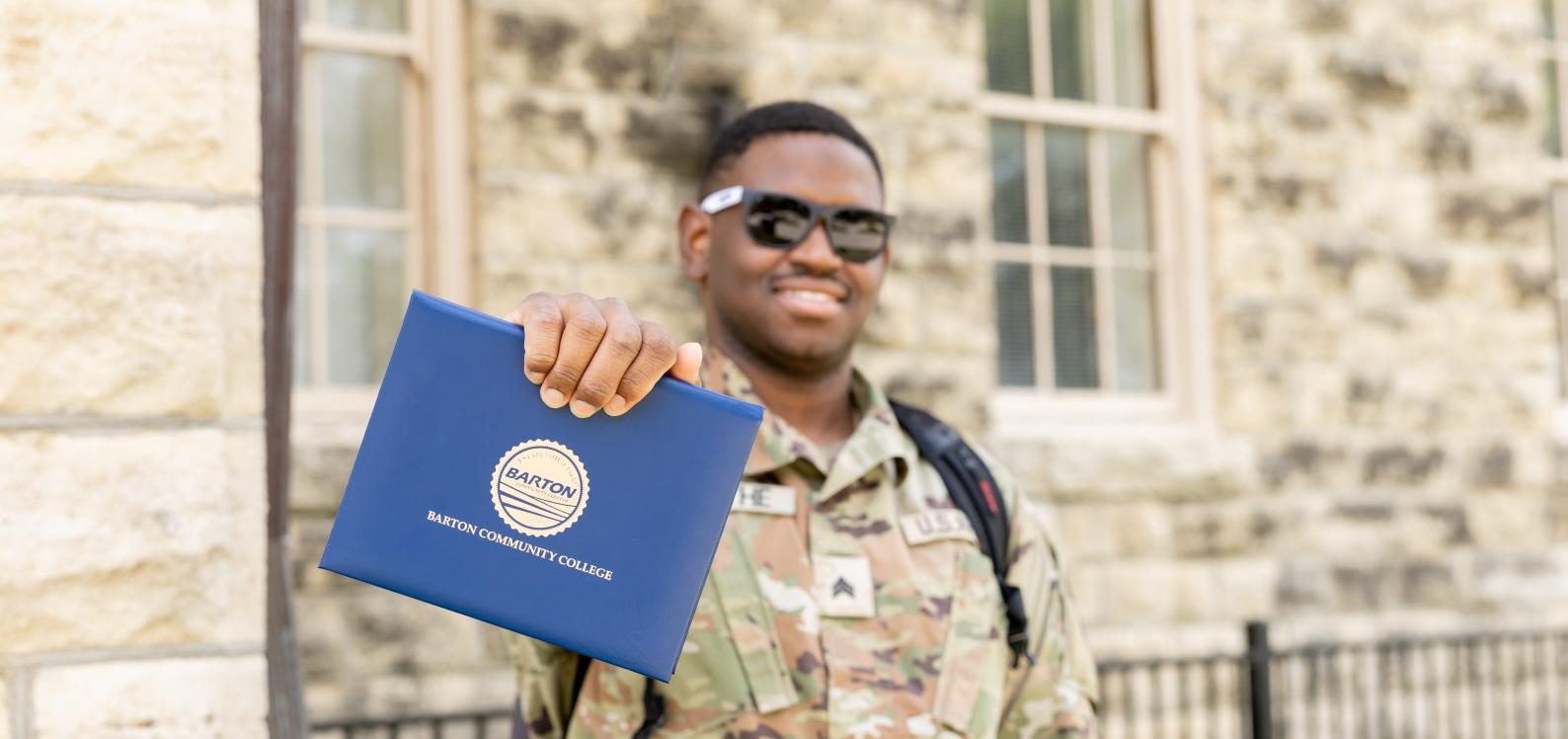 A student on the Fort Riley campus holds a commencement degree folder